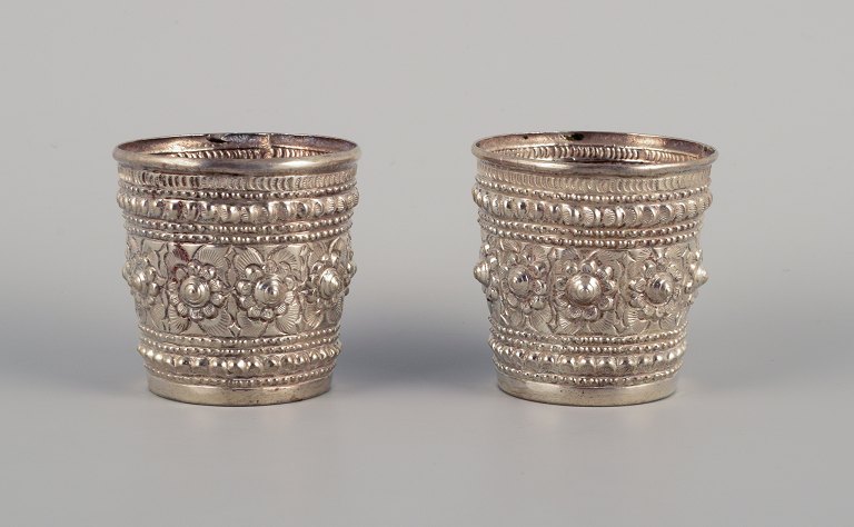 Chinese silversmith. Two small goblets richly decorated in relief with flowers 
and ornaments.