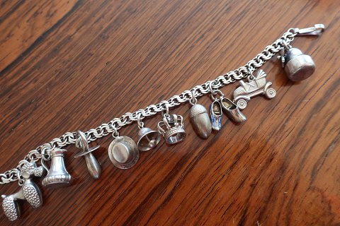 Bracelet, silver, Bismark, with 10 charms
- Poodle
- Jug
- Dummy
- Hat
- Bell
- Crown
- Acorn
- Wooden shoe
- Veteran car/ Vintage car
- Mill
Charms with partly worn down blue enamel
About 1960
L: 15cm
The bracelet and the charms never polis