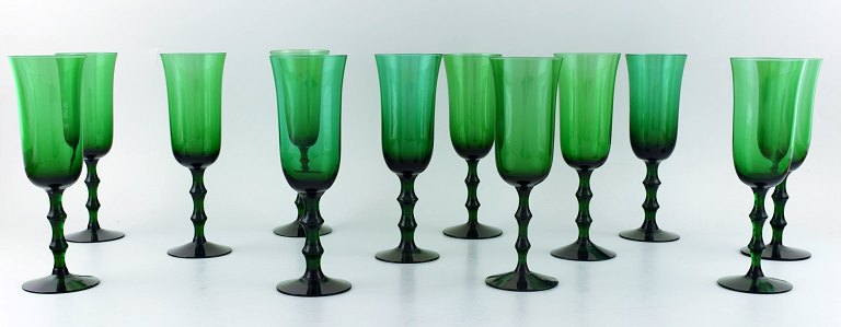 SIMON GATE ORREFORS, A set of 12 green champagne glasses in art glass.. 
