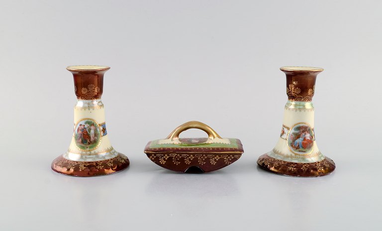 Two candlesticks and ink dryer in hand-painted porcelain. Romantic scenes and 
gold decoration. Vienna, early 20th century.
