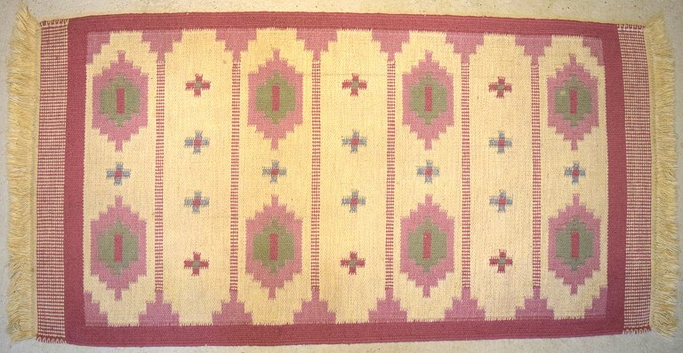 Swedish textile designer. Hand-woven RÖLAKAN rug in pure wool with geometric 
fields and clean lines in pink and sand shades. Mid-20th century.
