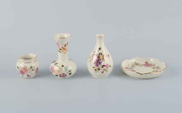 Zsolnay, Hungary, four-piece porcelain set consisting of three vases and a small 
dish. Hand-painted with flower motifs and insects on a cream-colored background.