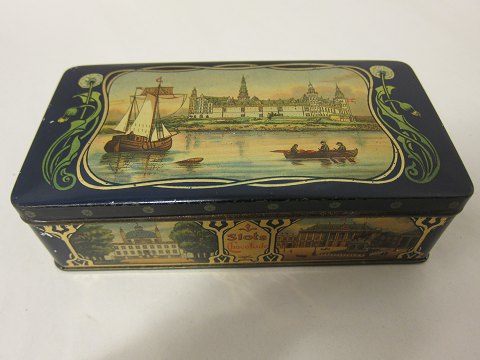 An old chocolate box/can from the Elvirasminde, Aarhus, Denmark 
Text: Slots Chokolade (Castle chocolate)
The box/can has very beautiful pictures as decoration 
L: 17cm
W: 8,5cm
H: 5cm
In a good condition but old