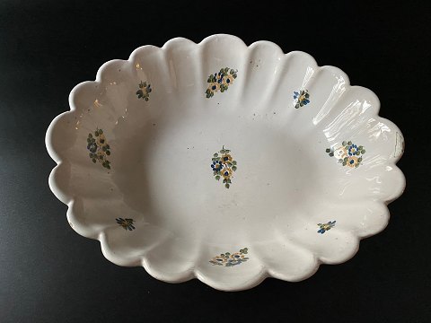 Antique, European, tin-glazed faience bowl with wavy edge and floral motif.