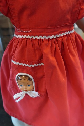 Pinafore / Apron for the child with a doll face placed at the front
This is a very special pinafore, where a doll face is placed in a cavity/hole 
at the pocket. It is possible to take the face out/move the face away when the 
pinafore is to be washed