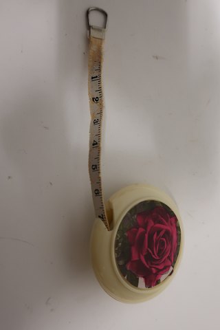 Measuring tool in a round holder, the holder is with a rose decorated
The measuring tape is pulled out from the box and let in again
Text: "Dean Measure" Made in England