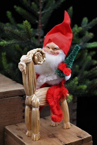 Gammel julenisse med vat skæg , nissehue , lille juletræ siddende på julebuk i 
halm. 
Højde:22 cm.