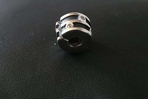 Charm til armbånd, fra  Pandora udført som cylender-formet med mønster med 
indlagt, klare hvide sten. 925 sterling sølv.