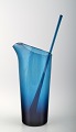 Lemonade pitcher with stir stick in dark blue glass.