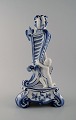 Royal Copenhagen. Lysestage af porcelæn, Musselmalet nr. 1/13 med fugl og putti 
siddende på trepasfod.