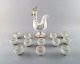 Bing & Grøndahl. Kande af porcelæn i form af hane, prop med hanekam. 12 
tilhørende krus af porcelæn med guldmalede detaljer.
