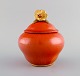 Nils Emil Lundström (1865-1960) for Rörstrand. Antique lidded jar in glazed 
ceramics. Beautiful orange glaze and flower in gold on the lid. Early 20th 
century.
