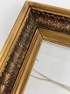 Old wooden gold frame with leaves and glass from 
the beginning of the 20th century