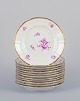 Bing & Grøndahl, Denmark. A set of twelve small plates with flower decorations 
in purple and gold trim. Hand-painted.