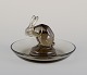 René Lalique, Frankrig. Tidlig Art Deco askebæger med hare i røgfarvet 
kunstglas.