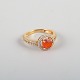 14 karat gold ring adorned with an orange opal and numerous brilliant-cut 
diamonds.