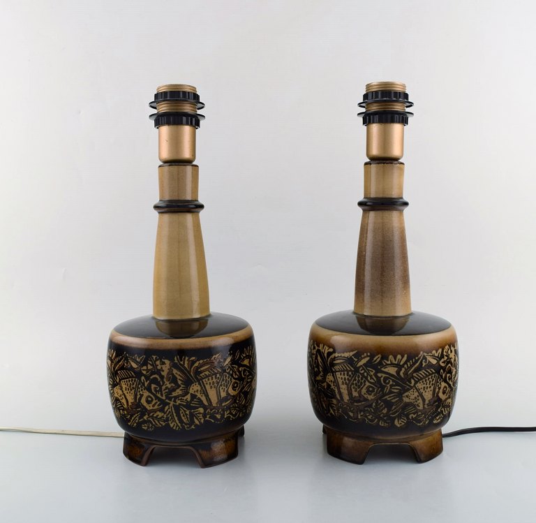 Nils Thorsson (1898-1975) for Royal Copenhagen. Two stoneware table lamps 
mounted on four feet decorated with fish motifs.
