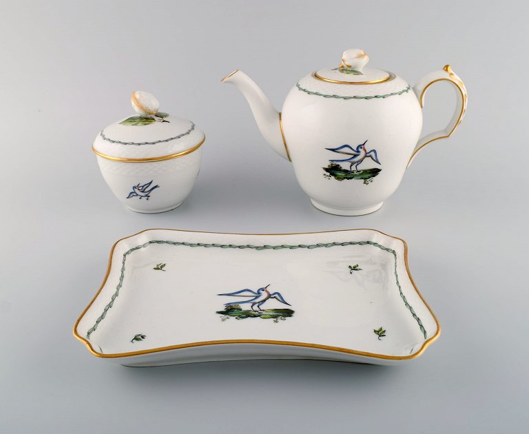 Royal Copenhagen teapot, sugar bowl and tray in hand-painted porcelain with bird 
motifs and gold decoration. Early 20th century.
