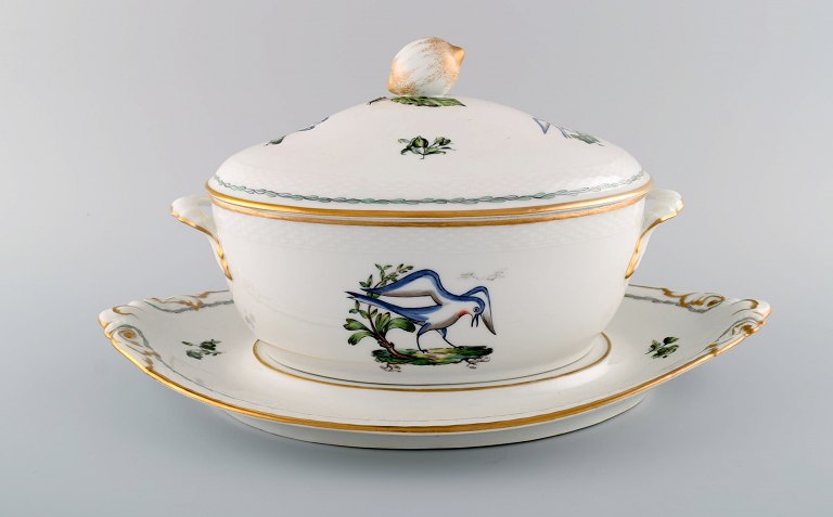 Stor Royal Copenhagen lågterrin med underfad i håndmalet porcelæn med 
fuglemotiver og gulddekoration. Tidligt 1900-tallet. 
