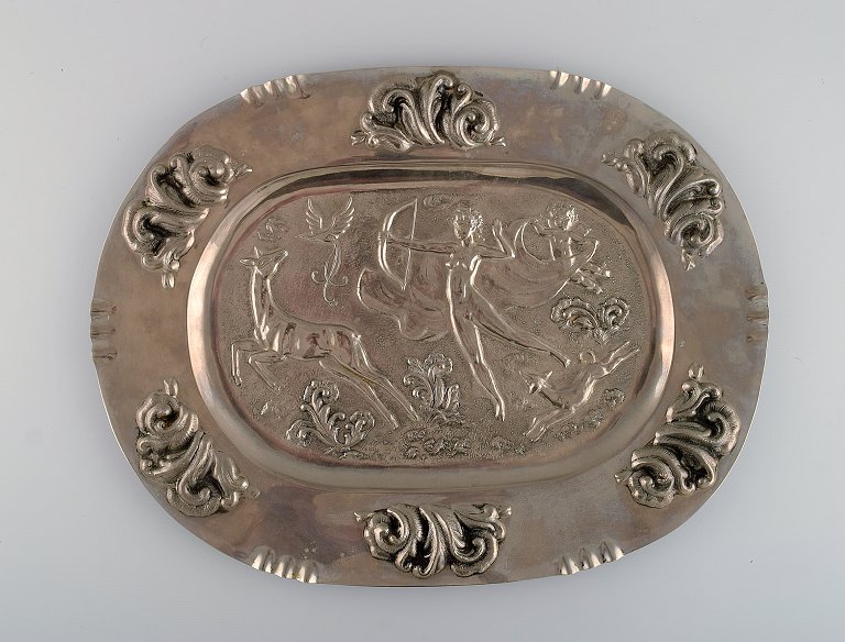 Svensk designer. Stort ovalt serveringsfad i metal med klassicistisk jagtscene. 
Swedish grace, 1910-1920.
