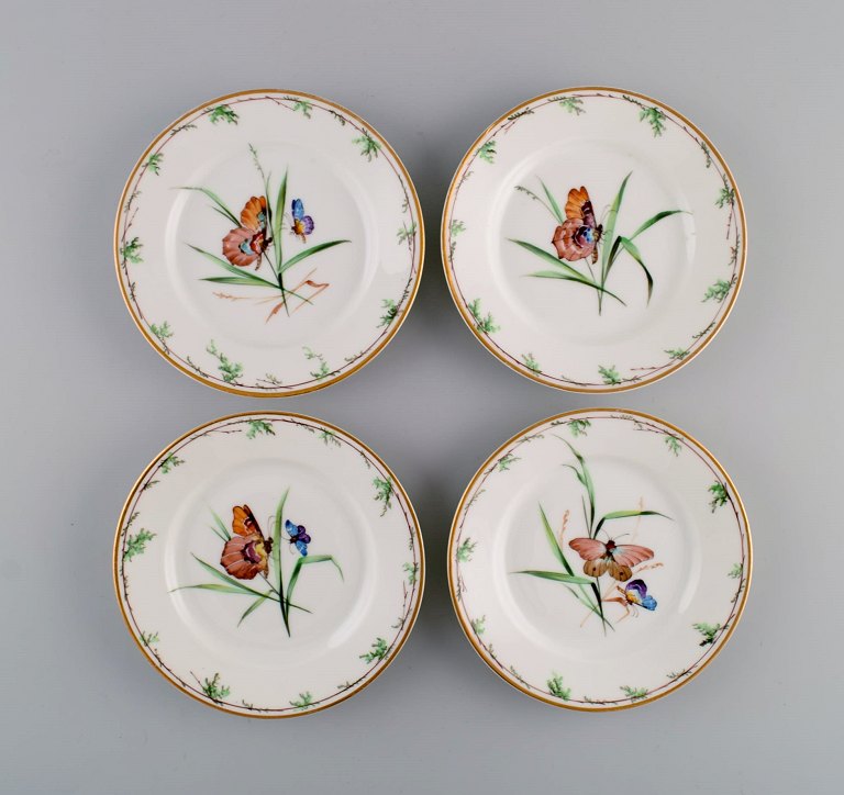 Fire antikke Royal Copenhagen sidetallerkener i porcelæn med håndmalede 
blomster, sommerfugle og guldkant. Midt 1800-tallet.
