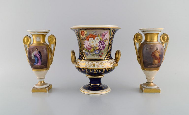 Three antique empire vases in hand-painted porcelain. Religious motifs, flowers 
and gold decoration. 19th century.
