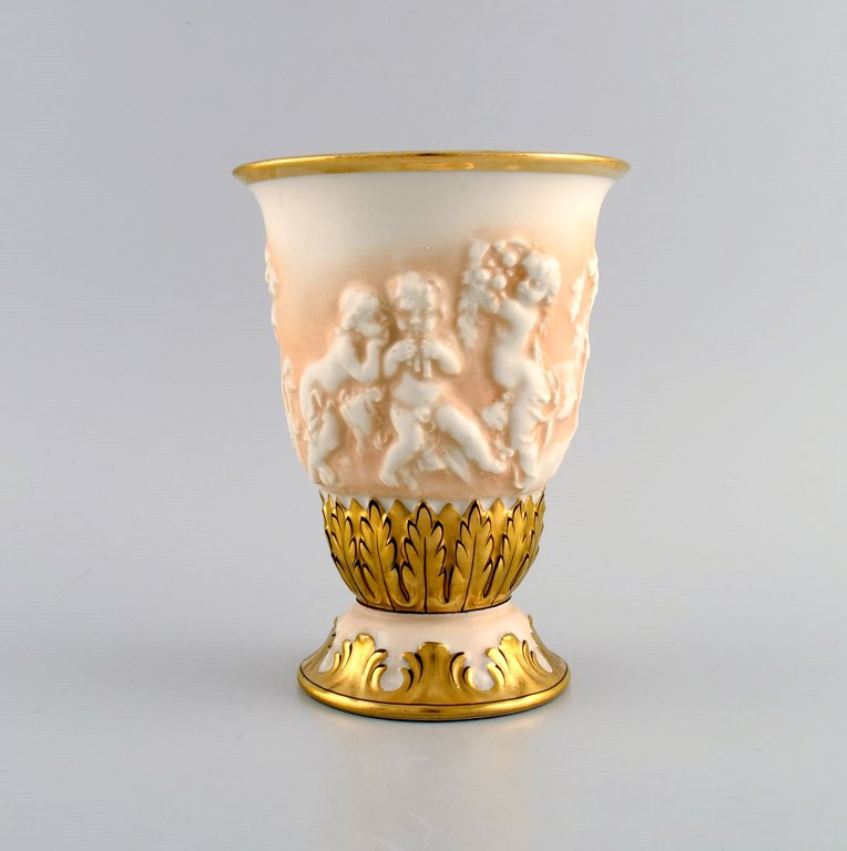Capodimonte, Italien. Antik porcelænsvase med putti i relief og håndmalet 
gulddekoration. Tidligt 1900-tallet.
