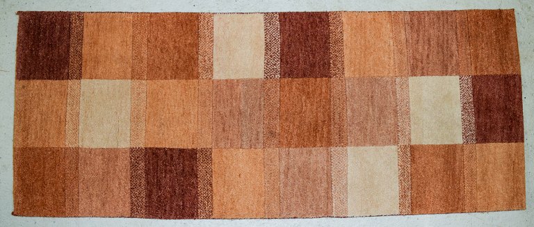 Milford, Sverige, tæppe i ren uld. Geometriske felter i røde, orange, og hvide 
nuancer. 1970