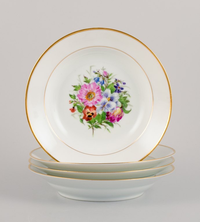Bing & Grøndahl, four deep plates in porcelain hand-painted with polychrome 
flowers and gold decoration.