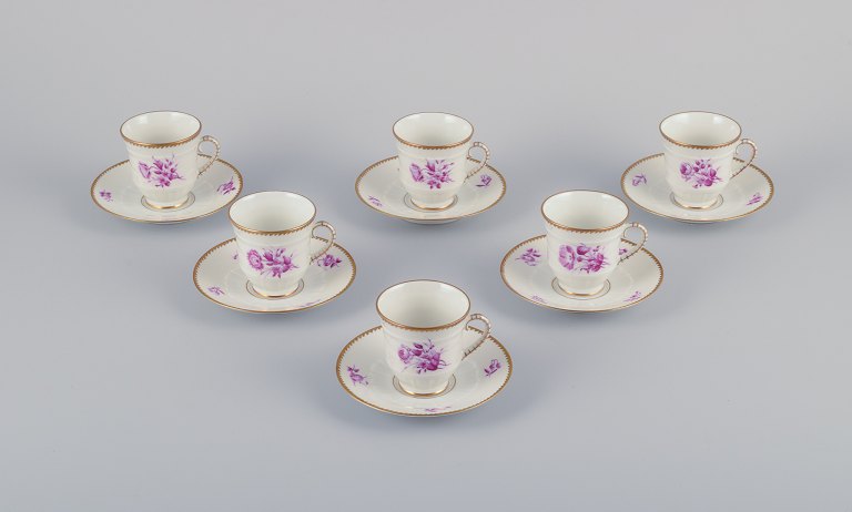 Bing & Grøndahl, Danmark. Et sæt på seks mokkakopper med tilhørende underkopper 
dekoreret med blomstermotiver i purpur og guldkant. Håndmalet.