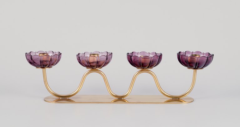 Gunnar Ander for Ystad Metall, Sverige.
Firarmet lysestage i messing med lilla glas formet som blomster.
