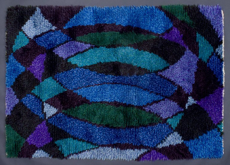 Svensk designer, håndvævet ryatæppe.
Geometrisk mønster i blå, violette og grønne farver.