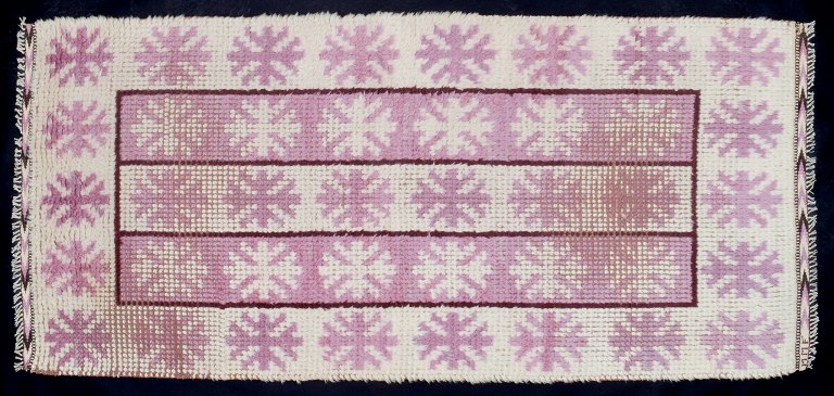 Märta Måås-Fjetterström (1873–1941), svensk tekstildesigner. 
Unika håndvævet ryatæppe i uld i modernistisk design. Lyserødt og hvid i 
geometrisk mønster.