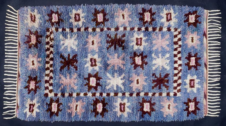 Märta Måås-Fjetterström (1873-1941)
“Tockarp”. Håndvævet “rya”-tæppe af uld med brun, hvid, lysebrun og lyserød 
geometrisk dekor på blå base.