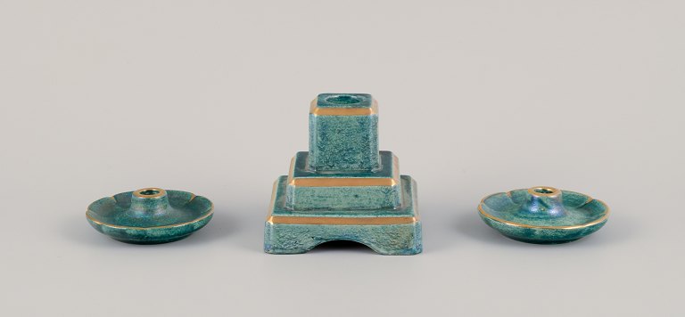 Josef Ekberg (1877-1945) for Gustavsberg, Sweden. Three candle holders with 
glaze in green-blue tones, gold decoration.