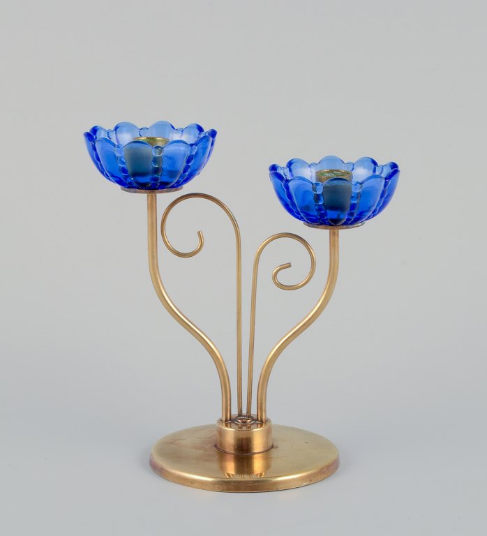 Gunnar Ander for Ystad Metall, Sweden. Brass candlestick holder with blue glass 
sleeves. For two candles.