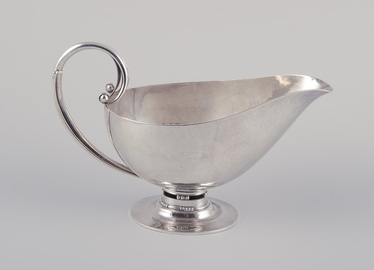 Johan Rohde (1856-1935) for Georg Jensen. Sterling silver gravy boat.
Hand hammered pitcher with handle and oval foot.
