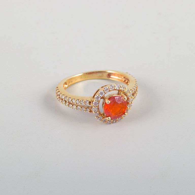 14 karat gold ring adorned with an orange opal and numerous brilliant-cut 
diamonds.